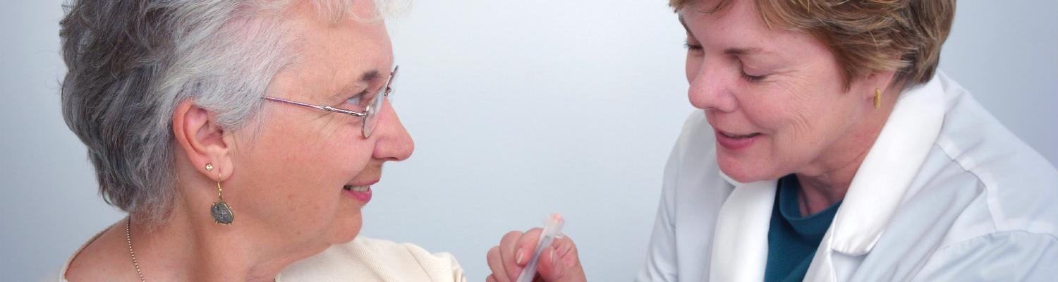 A doctor administers a shot in the arm of a senior patient
