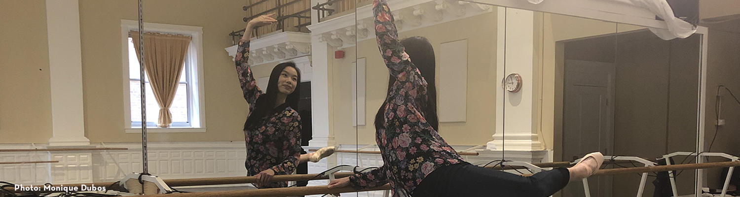 Ashley Chin-Mark stands in arabesque in front of a mirror in her practice studio