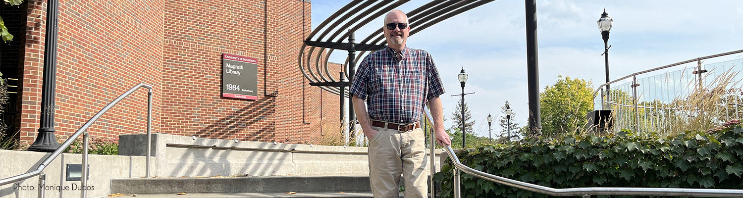 John Raabe stands on the steps of the plaza between Ruttan Hall and McGrath Library on the St. Paul campus