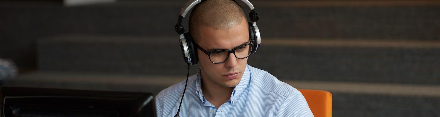 Man wearing headset working on two computers