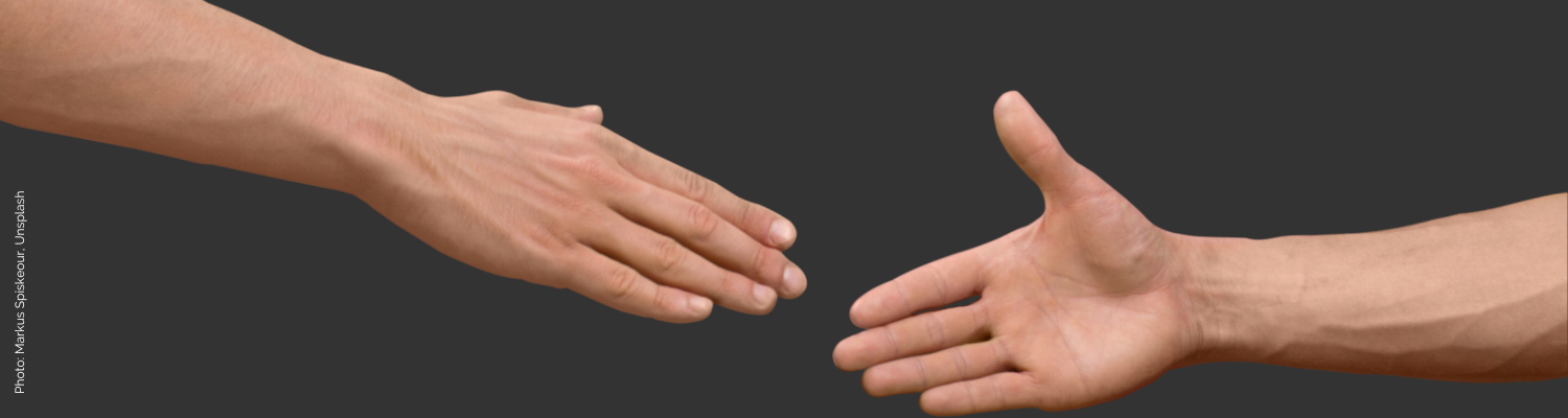 Two outstretched arms with open hands reach toward each other before a dark background