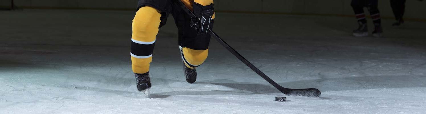 Hockey player legs, stick, and puck