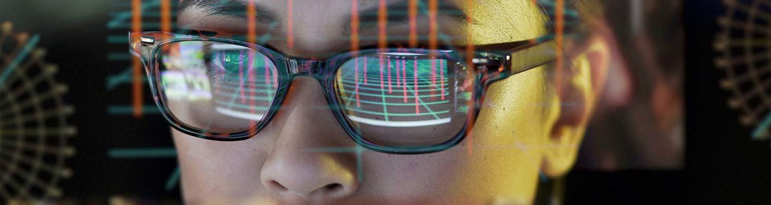 Woman looking at data on screen which is reflected in her glasses