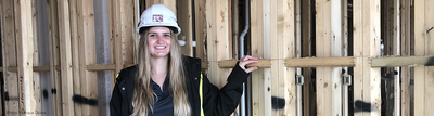 Cami Vargo stands inside a building under construction surrounded by wood framing