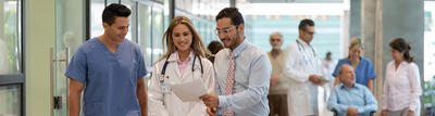 Three health care workers reveiwing paperwork in hospital hallway