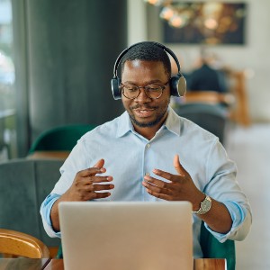 A man in headphones gestures during an online meeting.