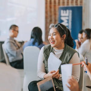 A woman cheerily holds a conversation during a conference.