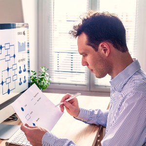A man sits at a computer, studying a spreadsheet.
