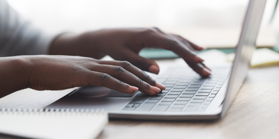 A Black woman's hands rest on a laptop keyboard